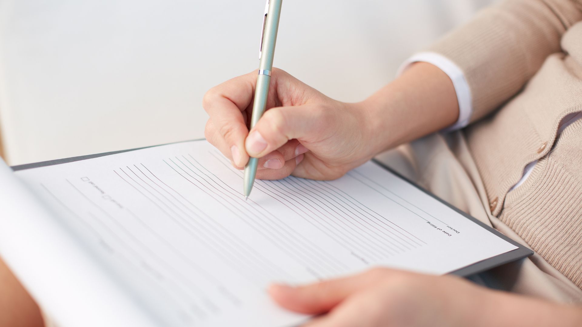 A person is filling out a form on a clipboard with a pen.